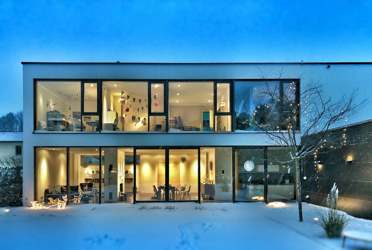 Modernes Haus in der Abenddämmerung mit warm beleuchteten Fenstern